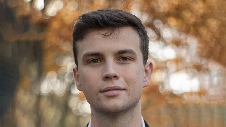 A man with short hair, with autumn leaves in the background. A man with short hair, with autumn leaves in the background.